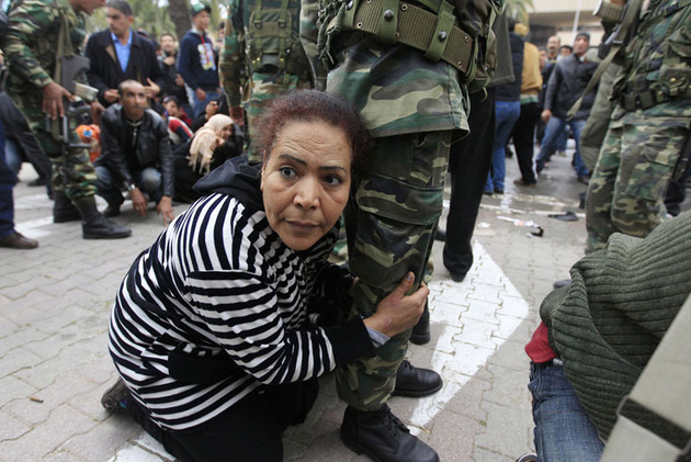 Демонстрантка хватается за ногу солдата, услышав выстрелы в воздух во время акции у штаба партии смещенного президента Зина Аль-Абдина Бен Али в Тунисе.