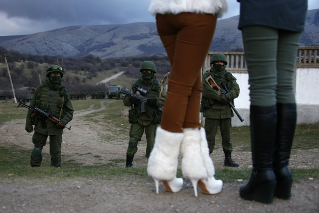 © Thomas Peter/Reuters 
Местные женщины смотрят на вооруженных людей около украинской военной базы в Перевальном