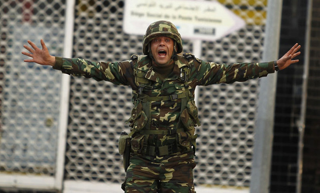 Тунисский солдат пытается успокоить демонстрантов во время беспорядков в центре столицы.
