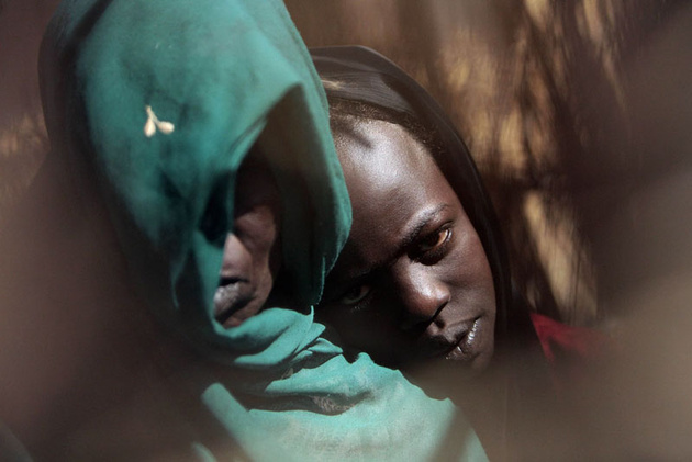 Одиннадцатилетняя Фатна Адам Хамед (справа), которую изнасиловали неизвестные вооруженные люди, прижимается к плечу матери в лагере для внутренних беженцев в Ньяле, Судан.