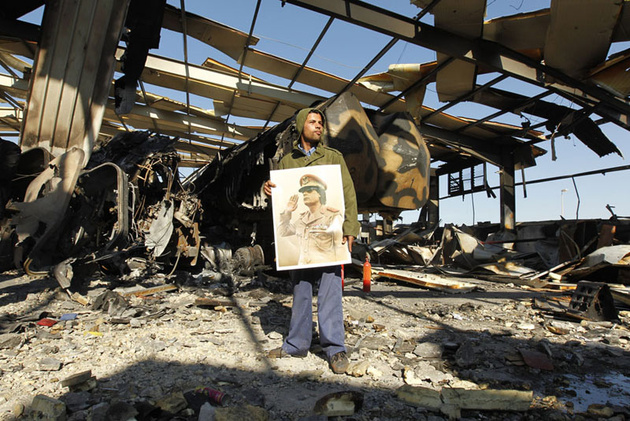 Мужчина с плакатом Каддафи в здании, разрушенном авиаударами НАТО, Триполи.