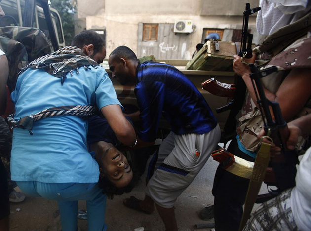 Медик и ливийский революционер несут тело убитого в бою за район Абу Салим в Триполи.