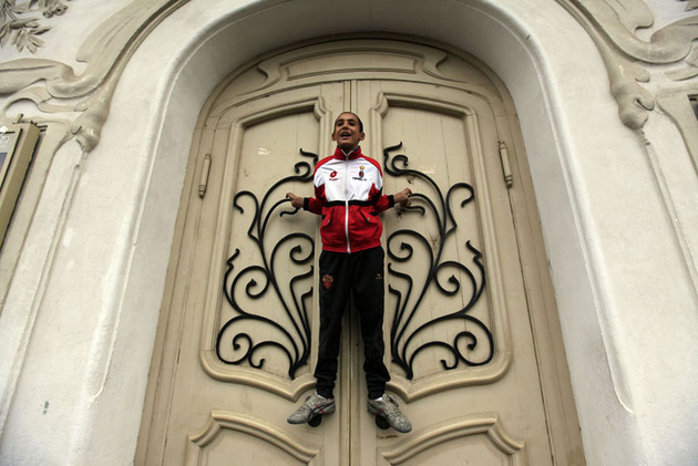 Мальчик висит на двери и выкрикивает лозунги во время антиправительственной демонстрации в Тунисе.