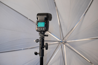 Вспышка Nikon SB-700, установленная на фотостойку. Зонтик, работающий на просвет, будет смягчать освещение от неё.