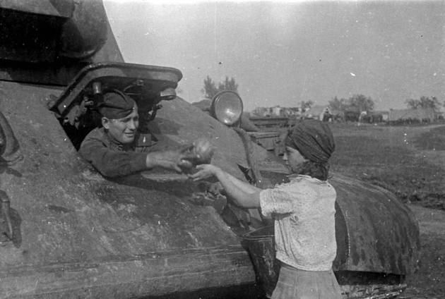 Жительница освобожденного украинского села угощает арбузами механика-водителя танка Т-34. 1943