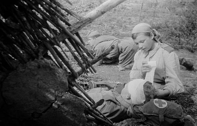 Санинструктор 705-го стрелкового полка старший сержант В.А. Пономарева перевязывает раненого в голову младшего лейтенанта Н.С. Смирнова. 1943