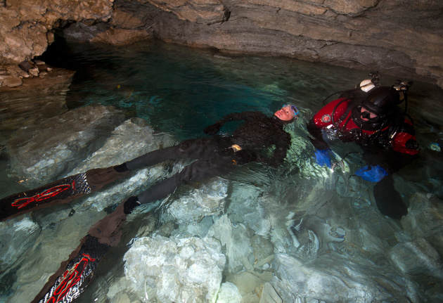 Входное озеро в Ординской пещере. Наталья Авсеенко делает дыхательные упражнения перед погружением на задержке дыхания. Справа — страхующий дайвер.