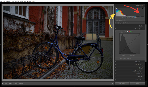 График гистограммы в Adobe Lightroom. Он отображается в окне Histogram и в инструменте Tone Curve («Тональная Кривая»). Этот снимок очень тёмный, что видно и по гистограмме: в левой части график «прилип» к границе поля (жёлтая стрелка), а справа — пусто (красная стрелка). То есть на фото много тёмных пикселей, а вот светлых участков нет.